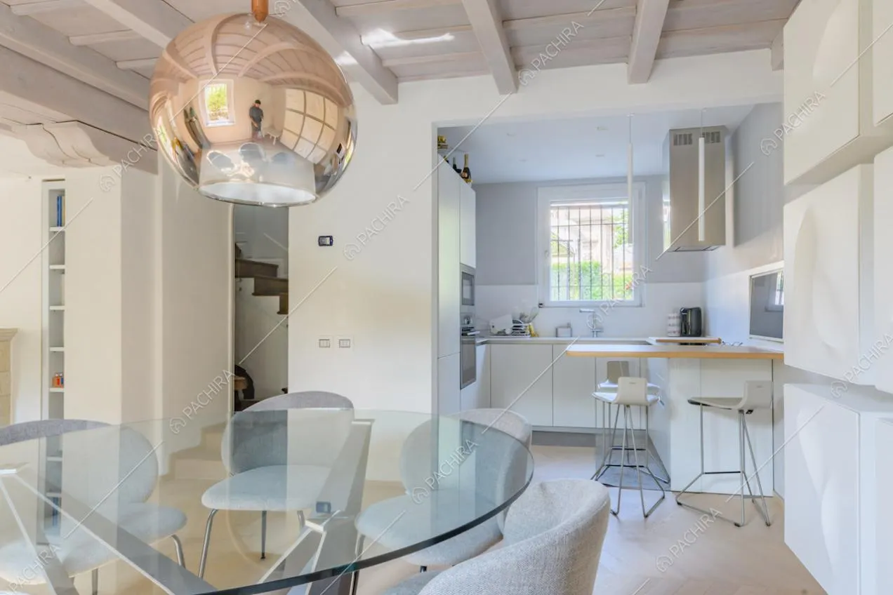 Vista sulla cucina bianca a parete nel luminoso salotto con pavimento in parquet