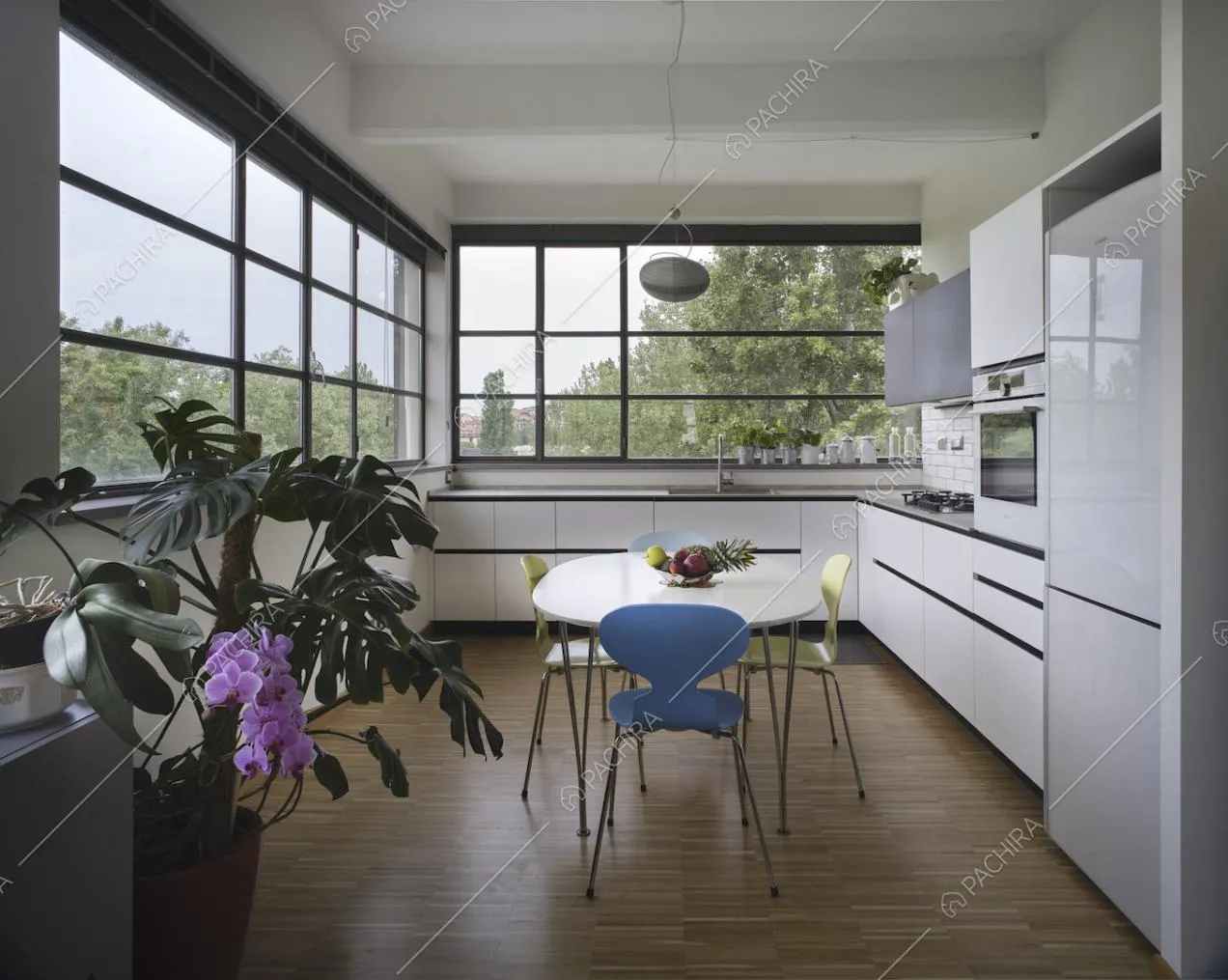 Cucina bianca a parete con tavolo da pranzo, finestre in stile industriale e pavimento in parquet