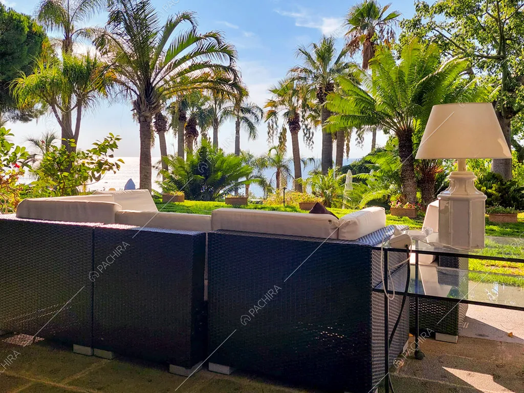 Divanetti da esterni nel grande giardino con palme e vista sul mare
