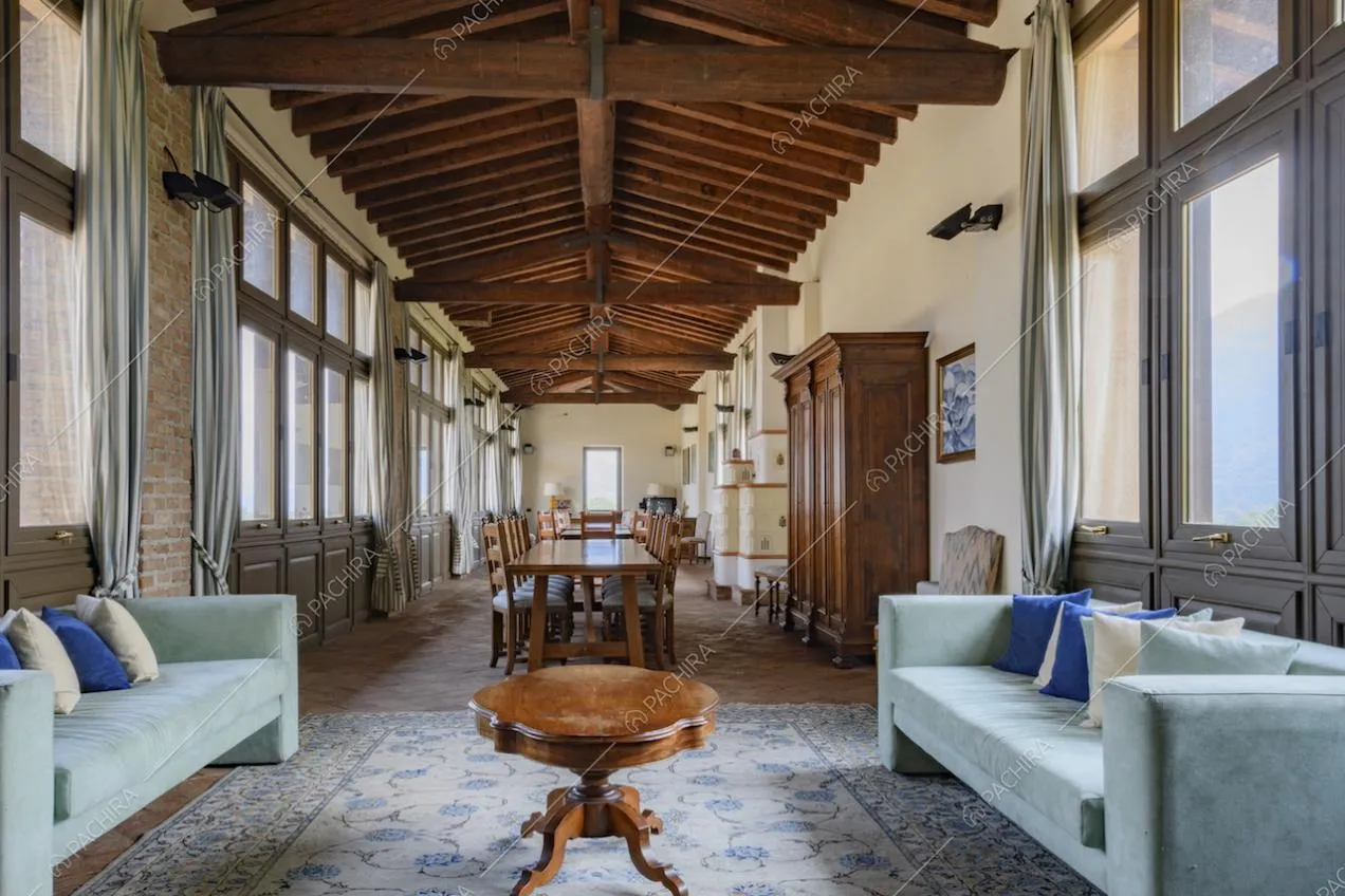 Divani azzurri e mobili antichi sotto al soffitto con travi in legno a vista