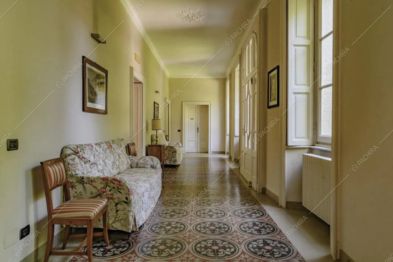 Ampio corridoio dalle pareti gialle, con pavimento in marmo e boiserie sul soffitto bianco