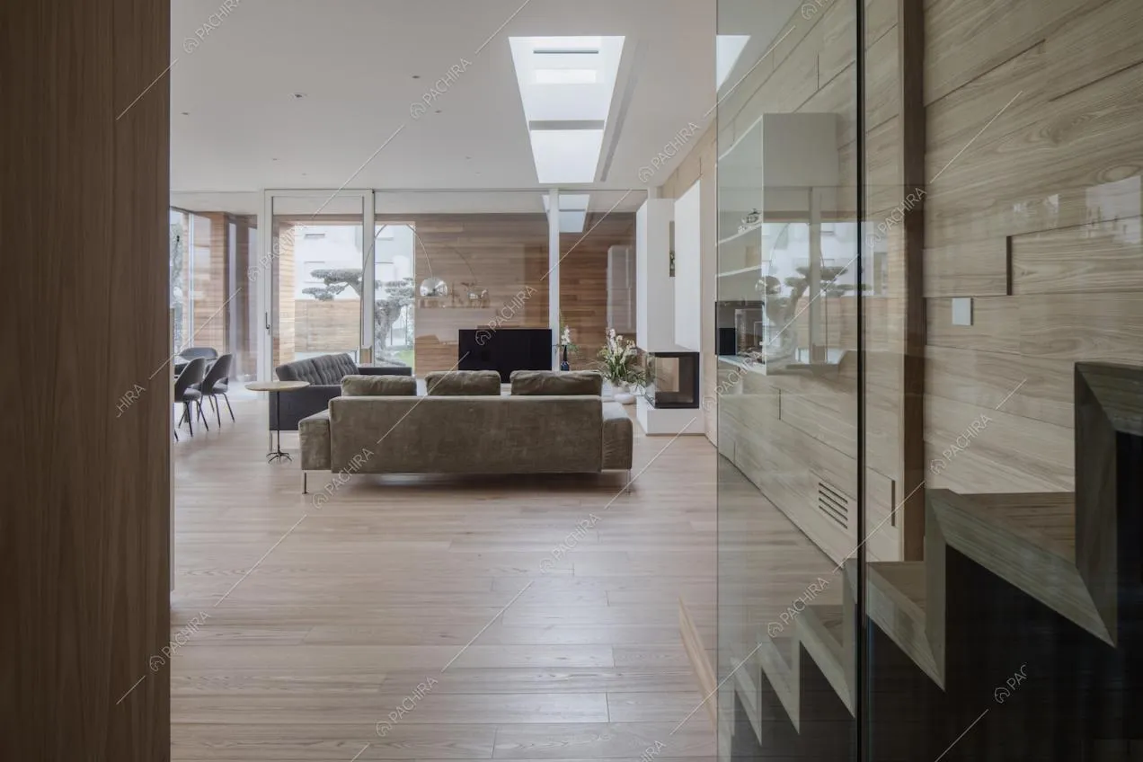 Dal sottoscala, vista sull'ampio soggiorno con doppio divano, pareti in vetro e pavimento in parquet