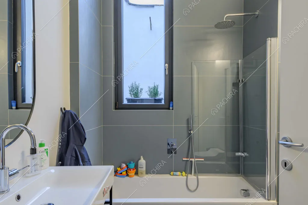 Bagno con grandi piastrelle grigie e vasca combinata con doccia