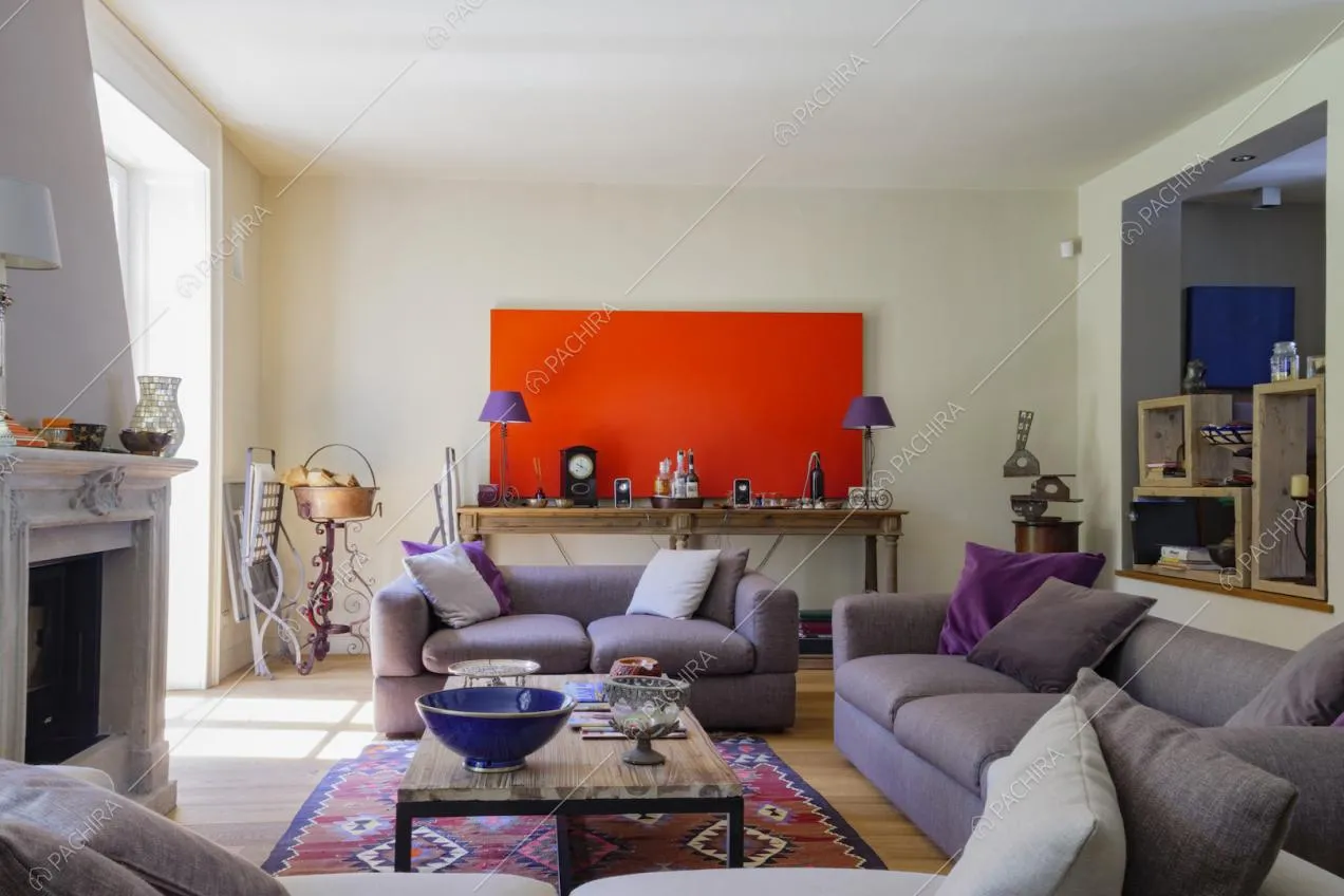 Salotto della villa con divani viola, camino e pavimento in parquet