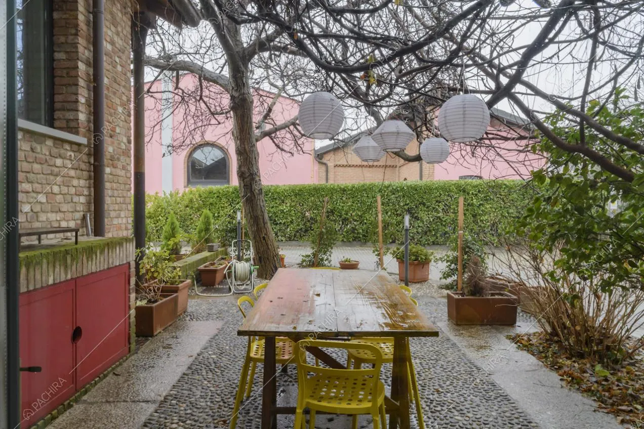 Giardino privato con tavolo da pranzo, siepe e vista sugli esterni in mattoni