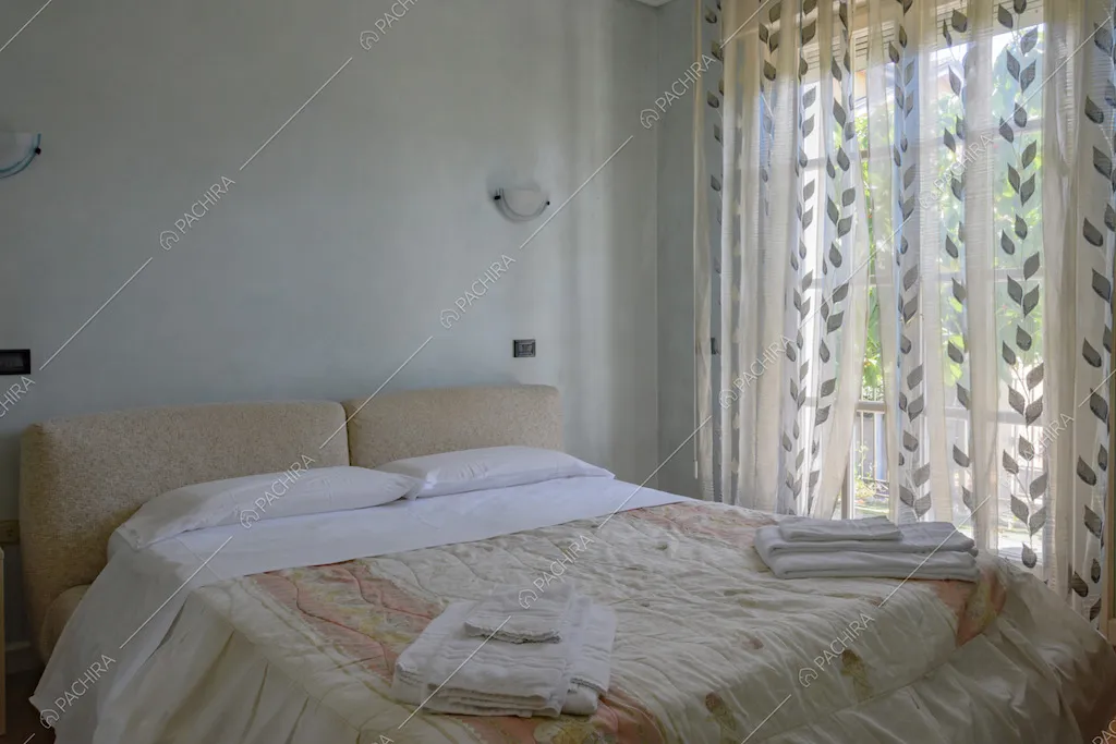 Letto matrimoniale e porta finestra con tende decorate