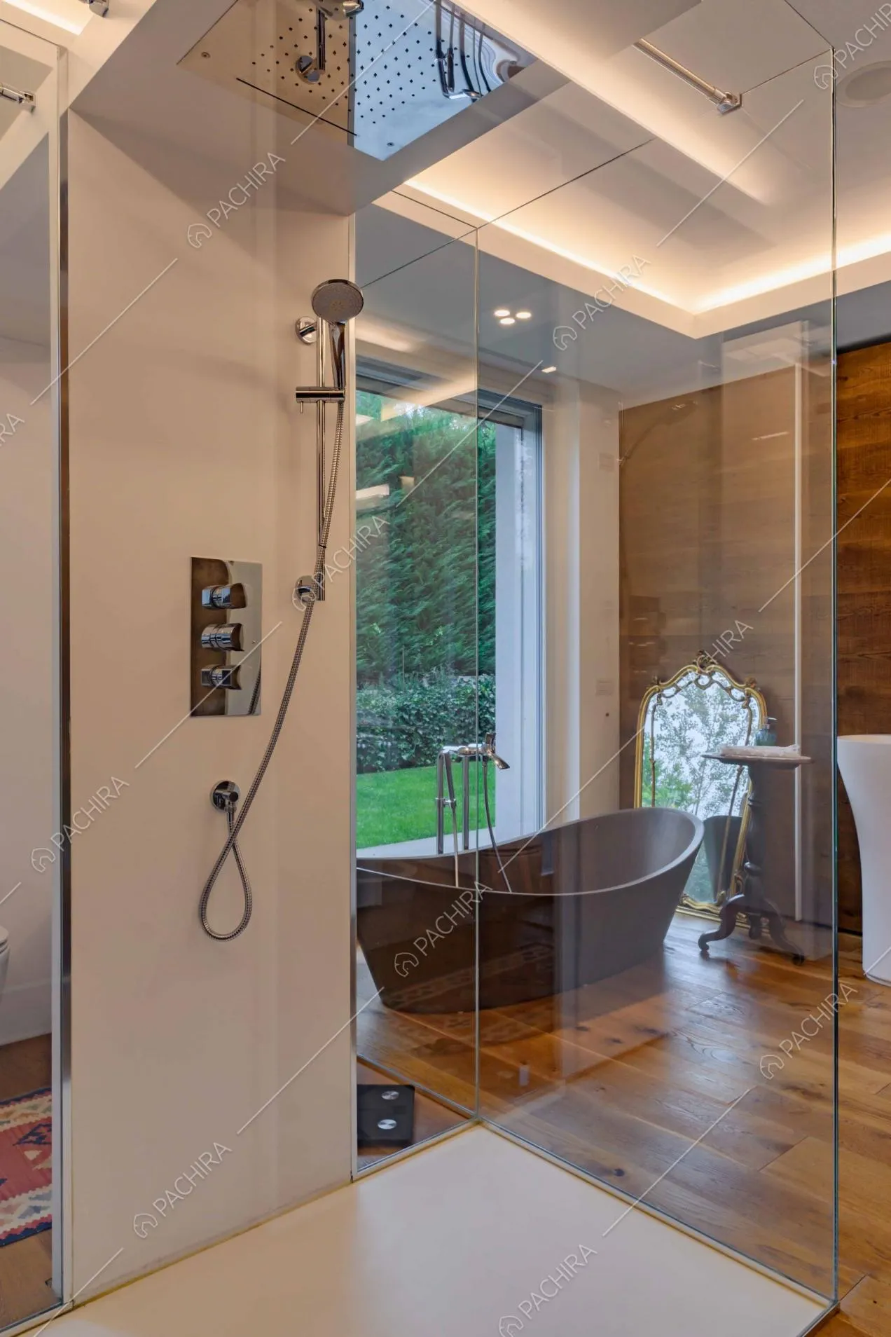 Dal box doccia con pareti in vetro vista sulla vasca da bagno in legno