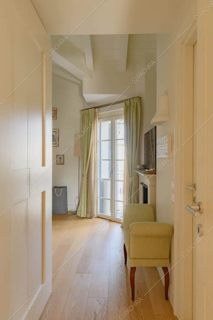 Corridoio di accesso alla camera con tende verdi, porta-finestra e pavimento in parquet