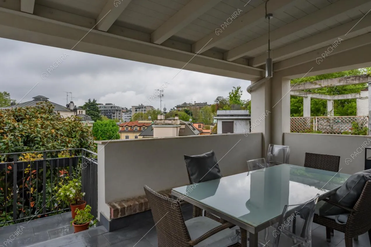 Terrazza coperta con soffitto in travi bianche a vista e tavolo da pranzo