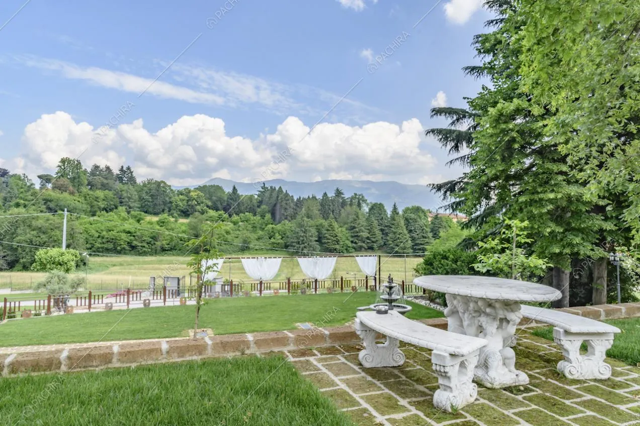 Nel parco della villa, panchine e tavolo in marmo lavorati e vista sulle colline brianzole