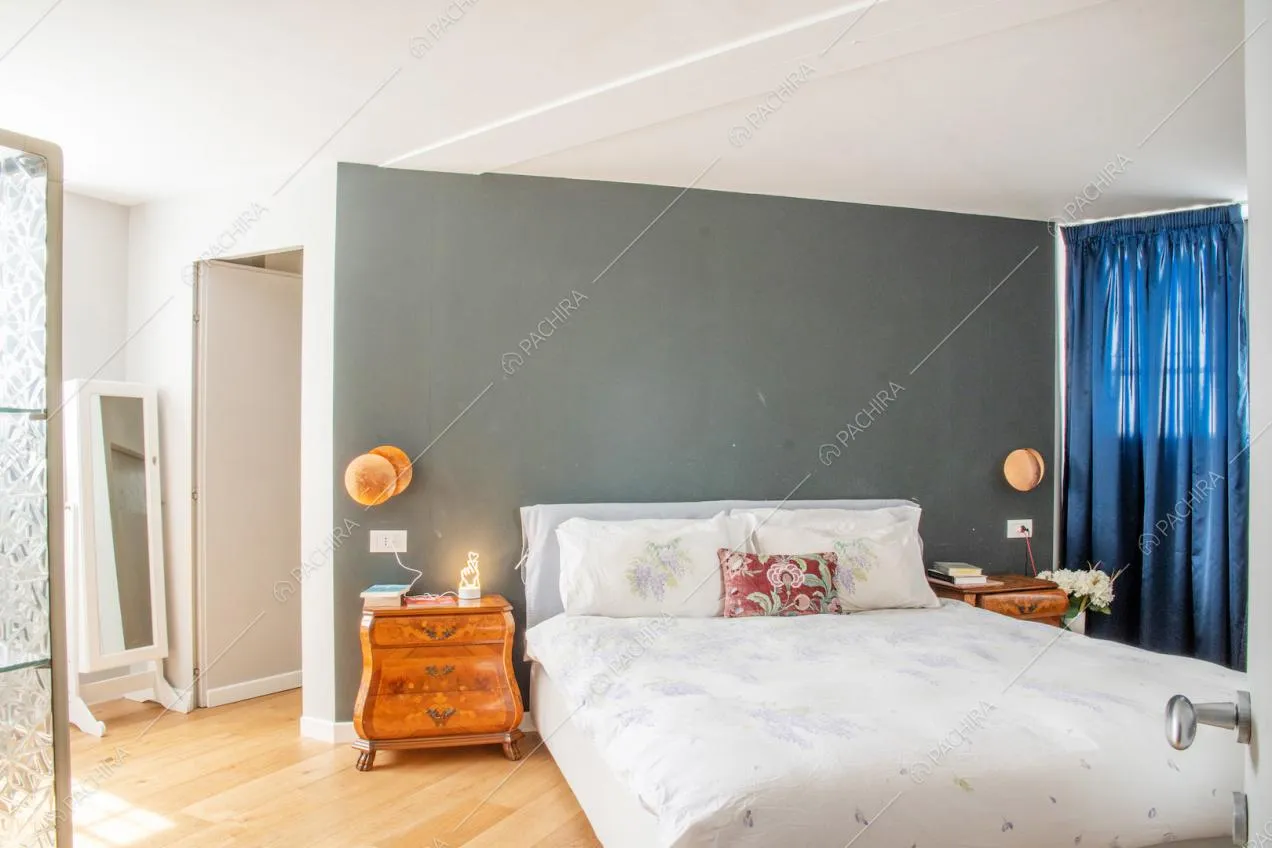 Camera da letto matrimoniale con pavimento in parquet, soffitto bianco e parete grigia