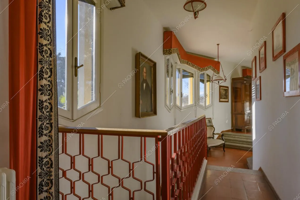 Corridoio con vista sulle scale, ringhiera rossa e cassone delle tapparelle dipinto con la stessa fantasia dei tendaggi