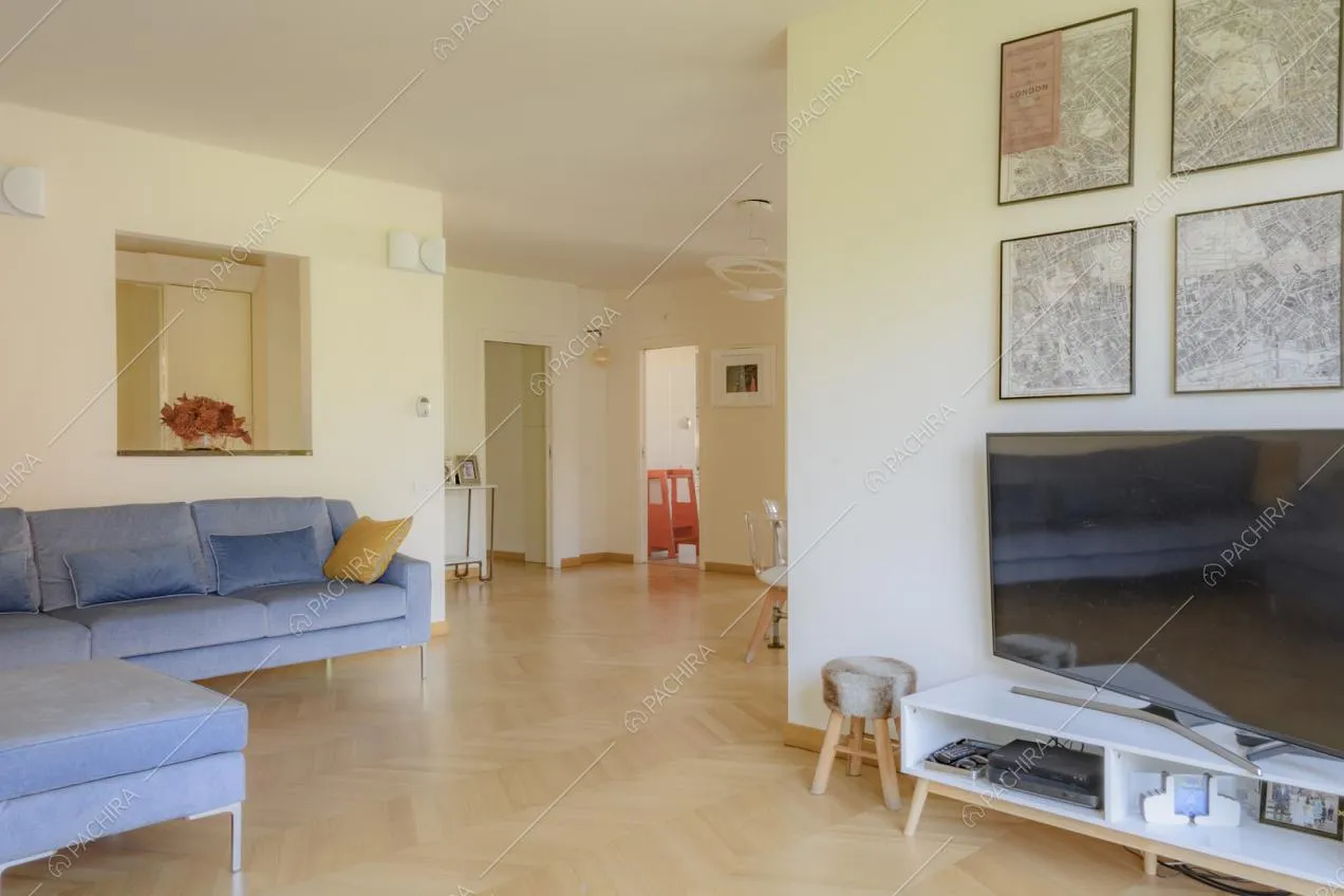 Televisore su piccolo mobile bianco e quadri appesi alla parete