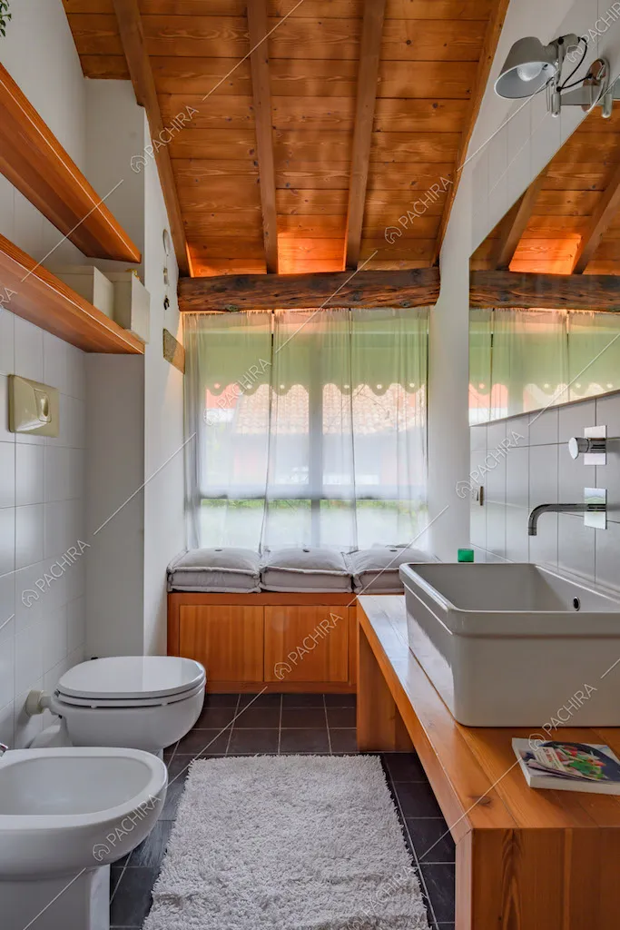Luminoso bagno con pavimento in piastrelle nere e travi a vista sul soffitto