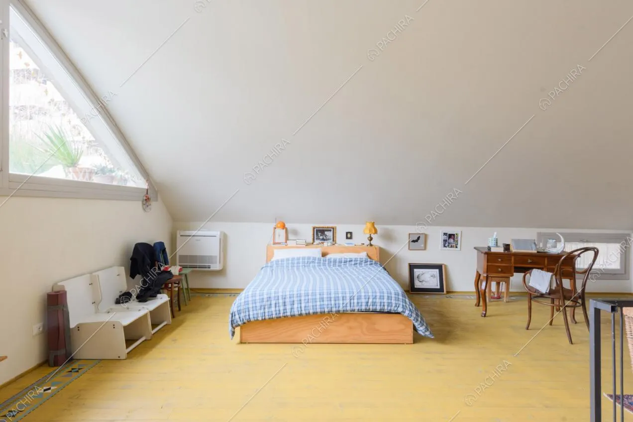 Letto matrimoniale sul soppalco con grande vetrata triangolare e scrivania