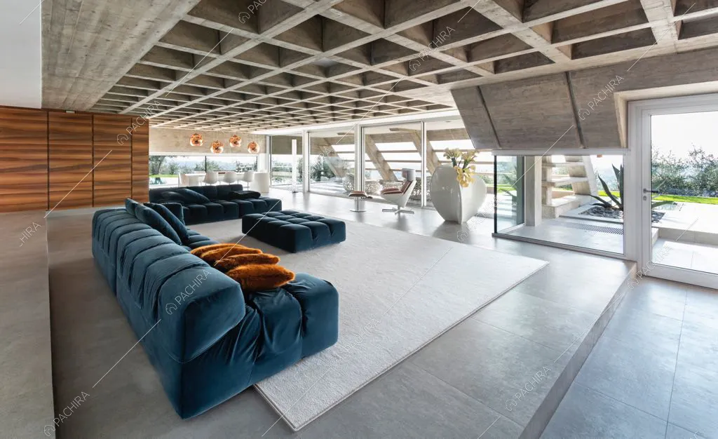 Zona giorno con vetrate e soffitto a cassettoni in cemento