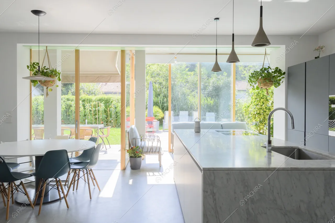 Zona giorno con cucina a vista e grandi vetrate