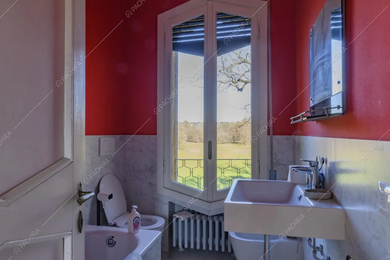 Bagno dalle pareti rosse e in marmo e vista sul parco