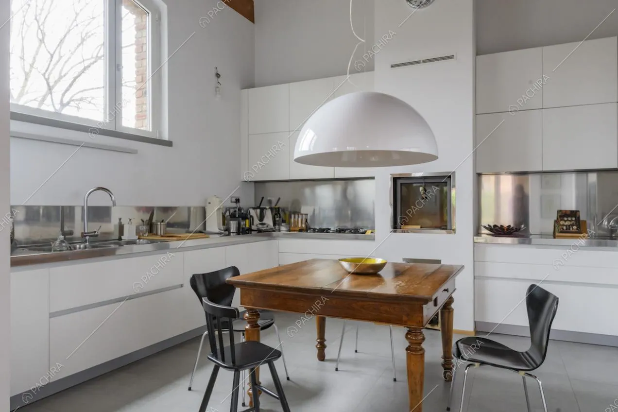 Luminosa cucina bianca a parete con fornelli a gas e lampadario bianco di design