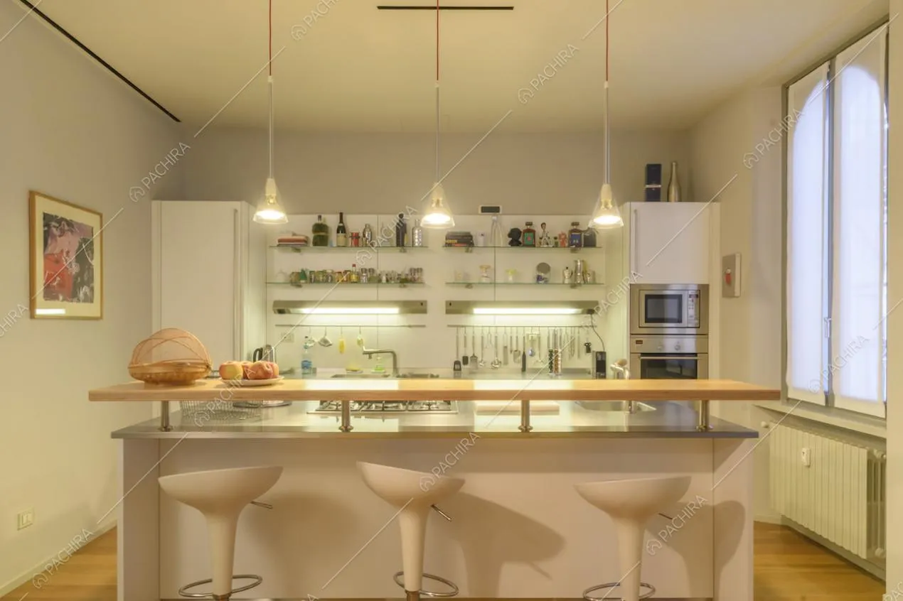 Cucina a isola con sgabelli bianchi e lampade di design