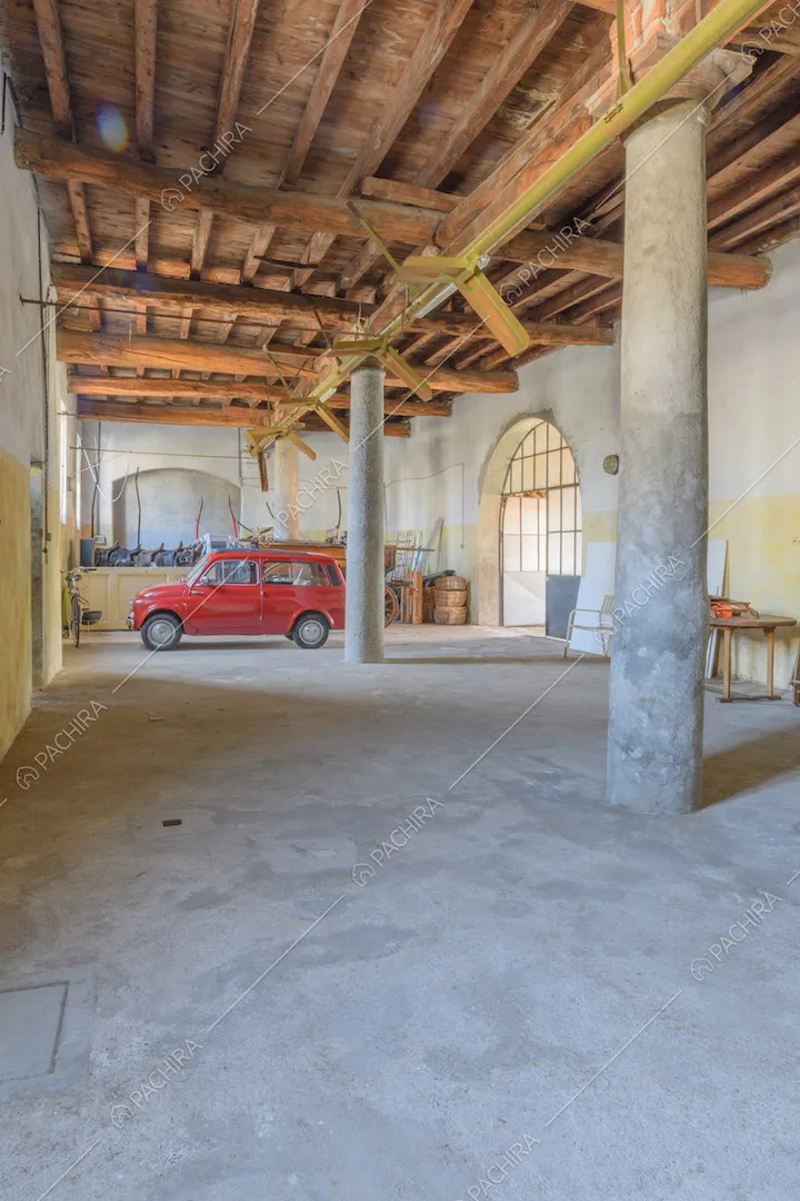 Grande garage con colonne in cemento e soffitto in travi in legno