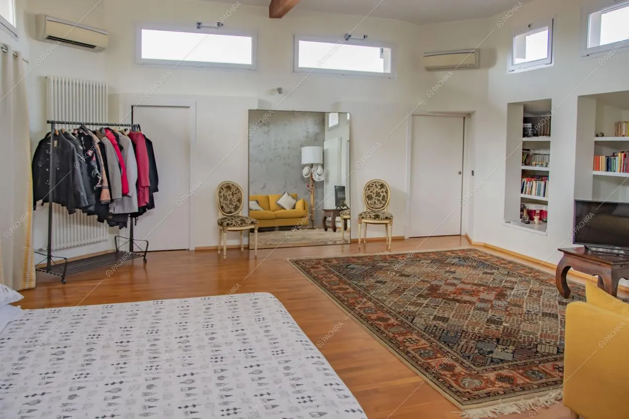 Ampia camera da letto matrimoniale con pavimento in parquet e divano giallo