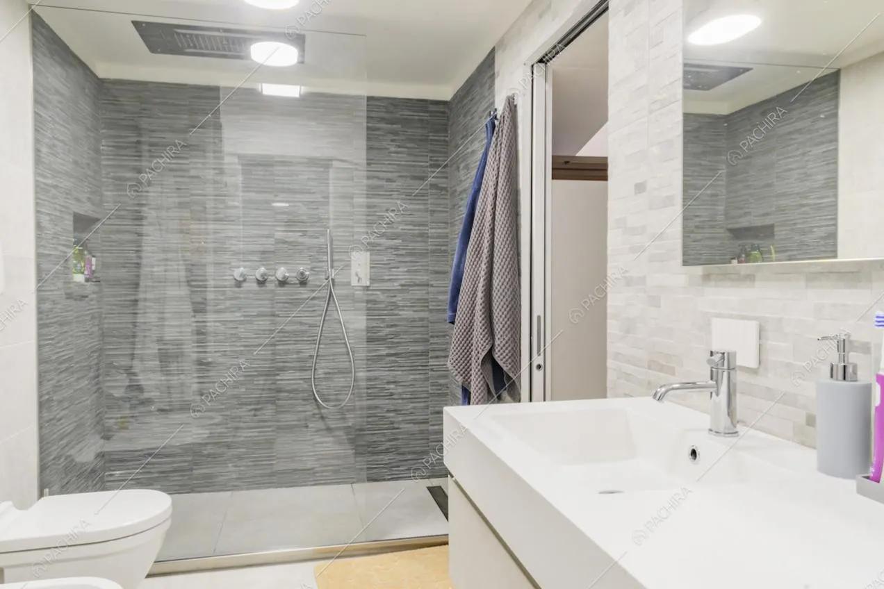 Bagno con porta scorrevole e ampio box doccia dalle pareti in pietra
