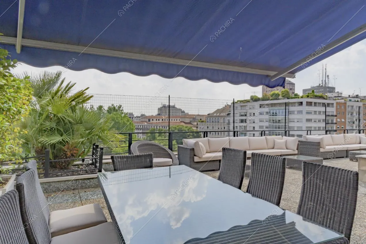 Tavolo da pranzo e divani da esterno sull'ampia terrazza con vista panoramica su Milano