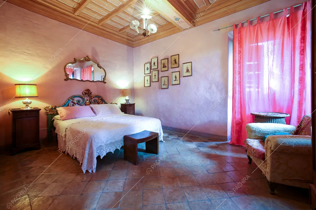Pareti rosa della camera da letto matrimoniale con pavimento in cotto e soffitto a cassettoni