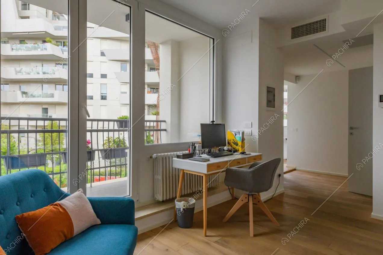 Pavimento in parquet nel luminoso salotto con scrivania e porta-finestra