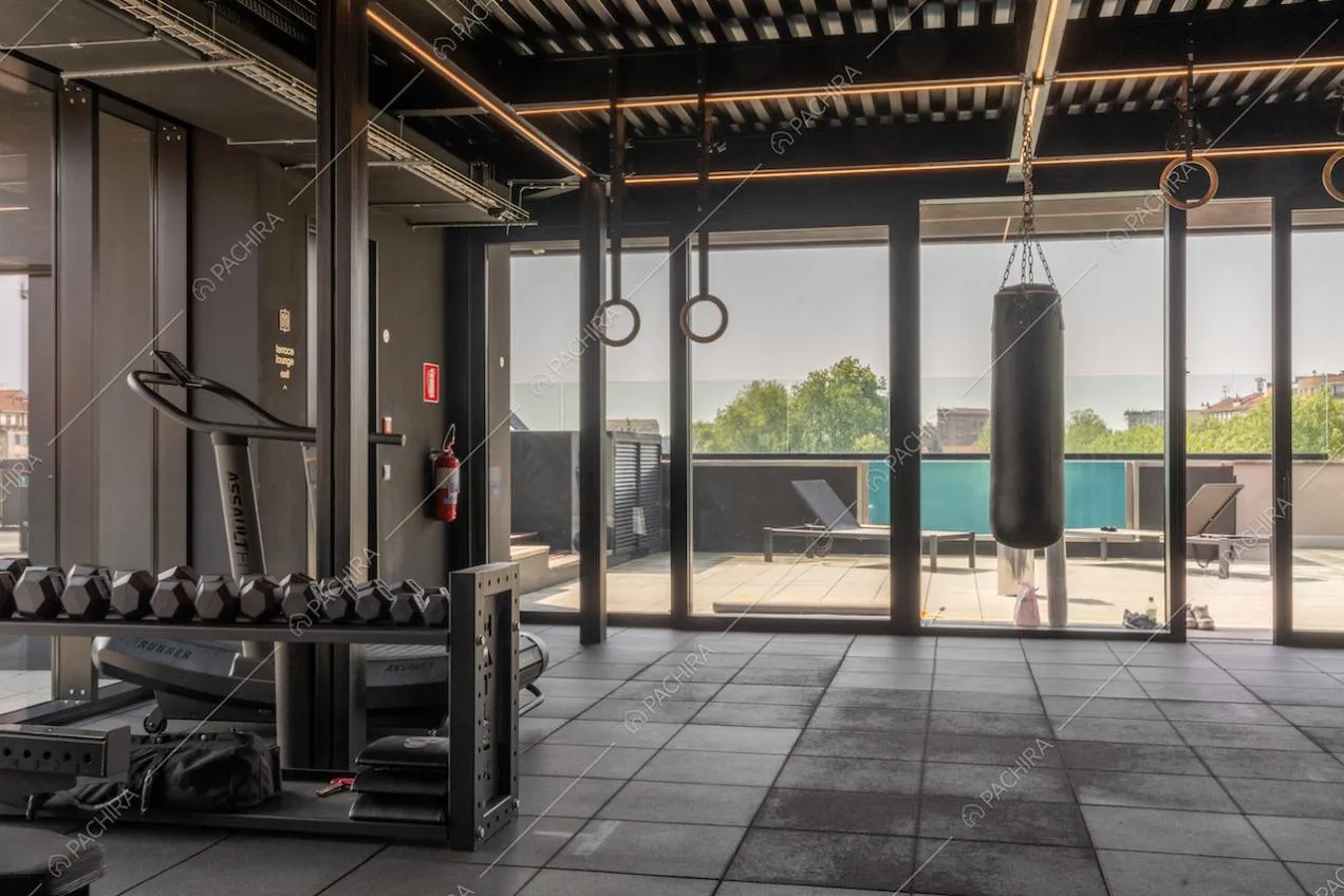 Palestra dell'attico con porte-finestre scorrevoli e vista sulla piscina della terrazza