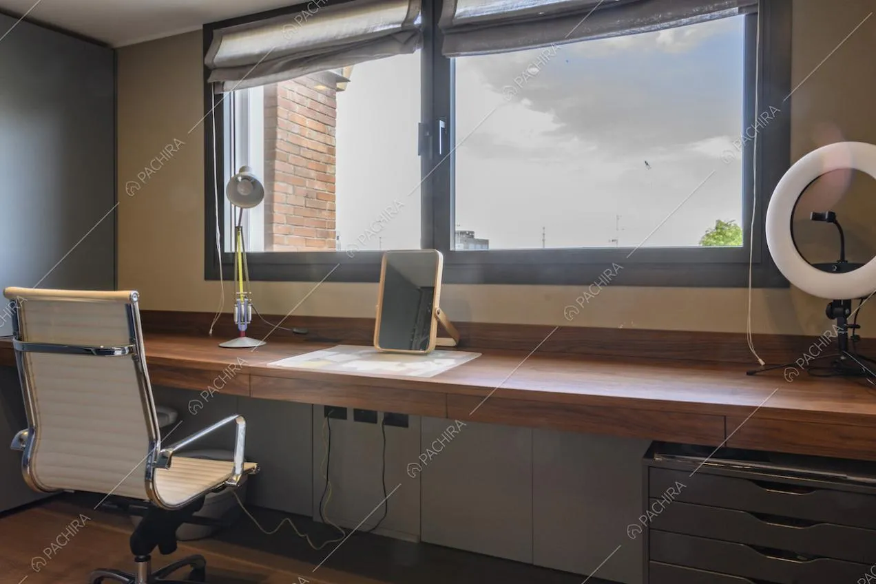 Lungo piano di lavoro in legno davanti a una finestra rettangolare