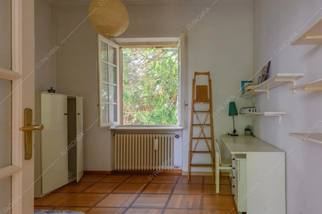 Luminoso studio con pavimento in parquet e scrivania bianca