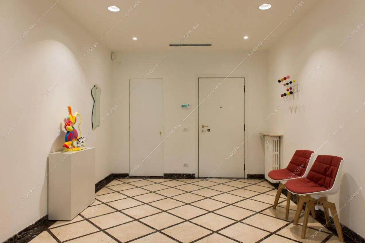 Ingresso dell'appartamento con pareti e soffitto bianchi e con sedie di design
