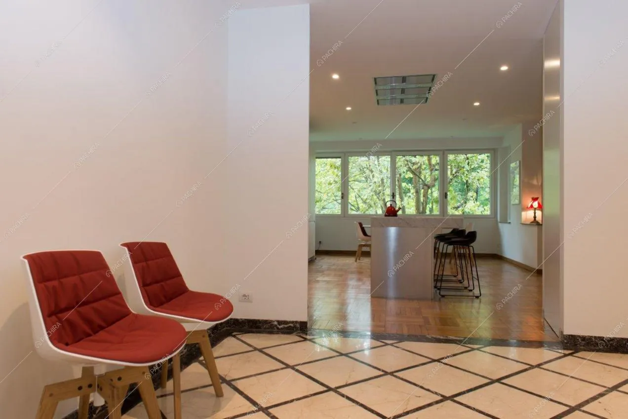 Dall'ingresso con sedie di design vista sull'isola e sugli sgabelli della cucina