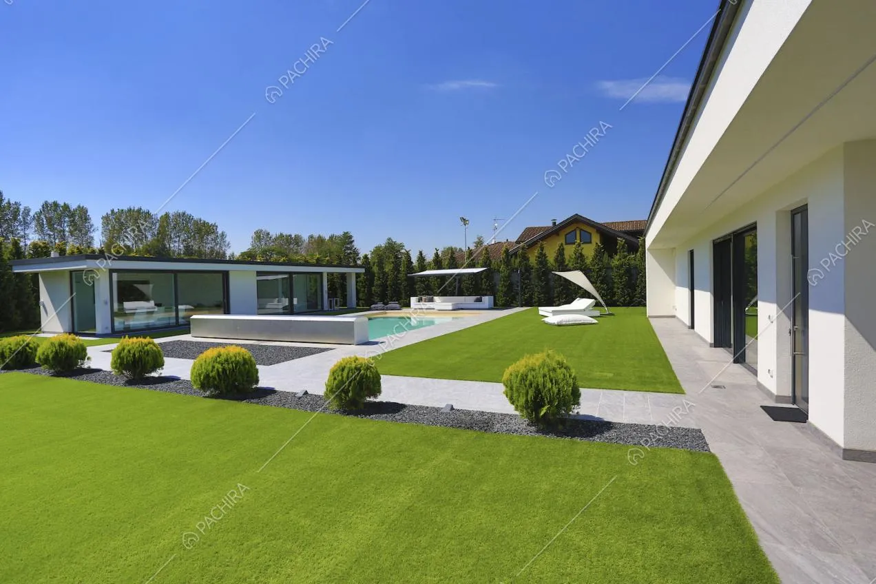 Giardino con vialetto in piastrelle e ciottolato con arbusti e vista sulla dépendance