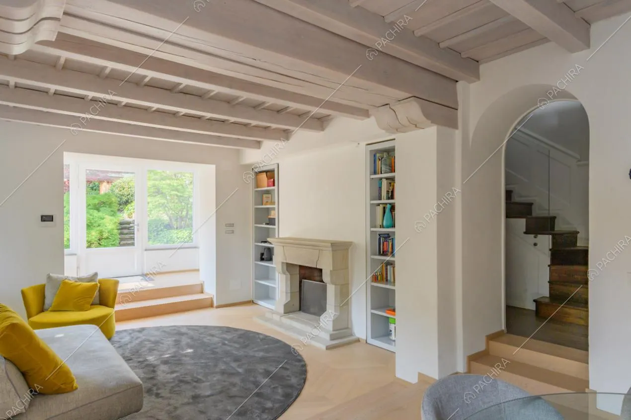 Grande salotto con camino, pavimento in parquet e soffitto in travi in legno a vista