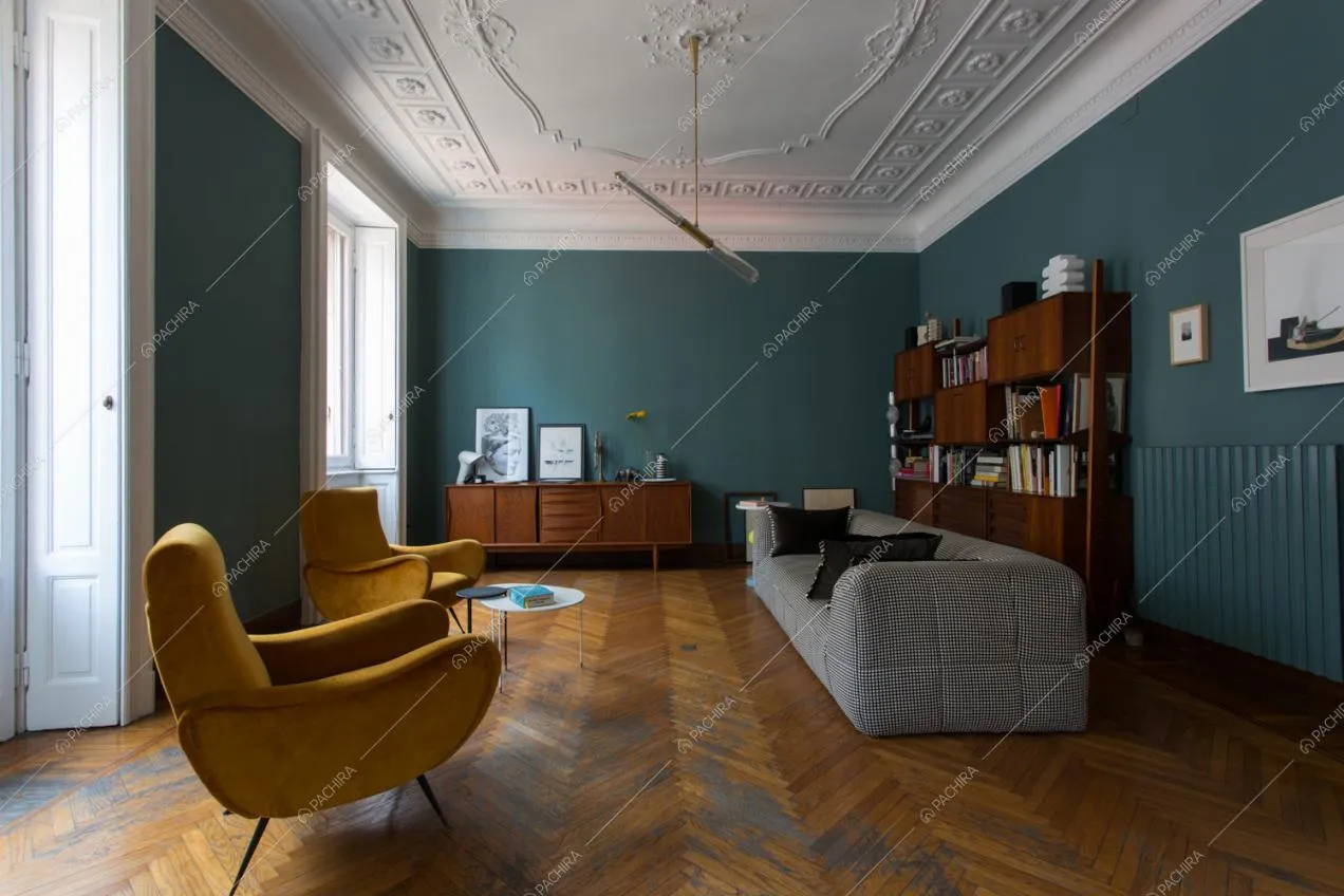 Pareti blu petrolio e soffitto con boiserie nel soggiorno