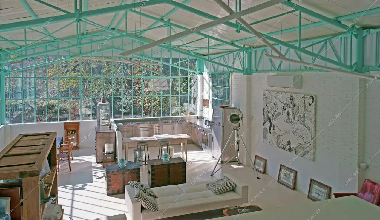 Open space con ampie vetrate e travi verdeacqua in metallo