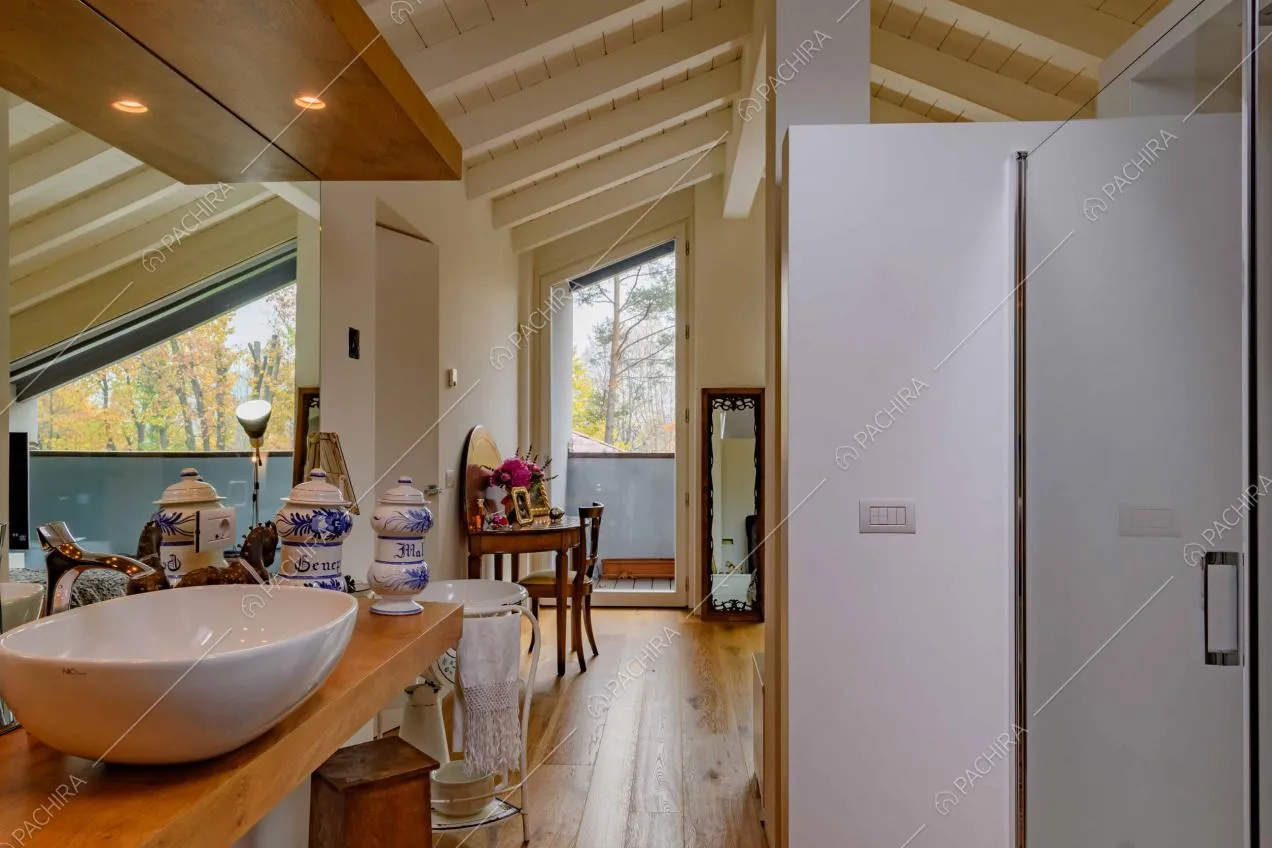 Bagno con pavimento in parquet, piano del lavandino in legno e porta-finestra per accedere al balcone