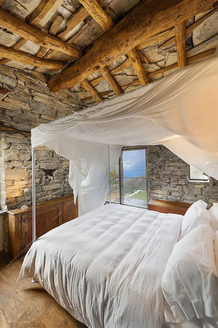 Letto a baldacchino, pareti in pietra, travi a vista