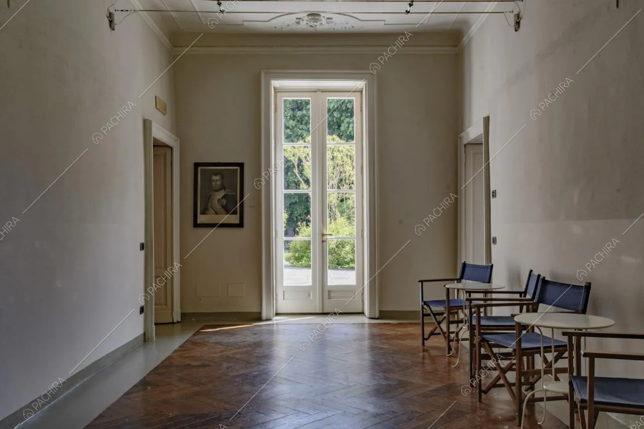 Stanza con boiserie sul soffitto bianco, porta-finestra e pavimento in parquet a spina di pesce