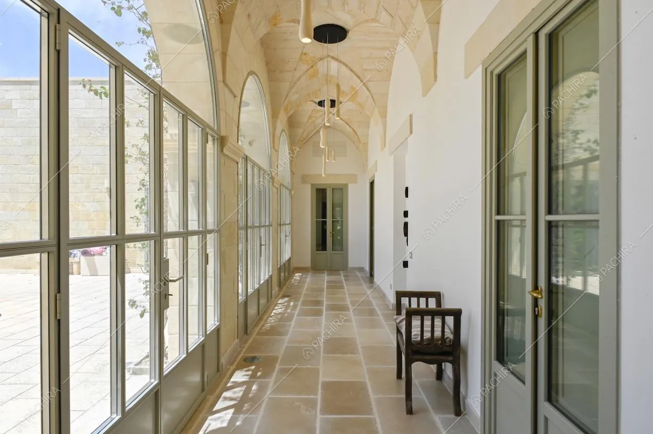 Luminoso corridoio con porte-finestre in stile industriale, pavimento in pietra e soffitto con più archi
