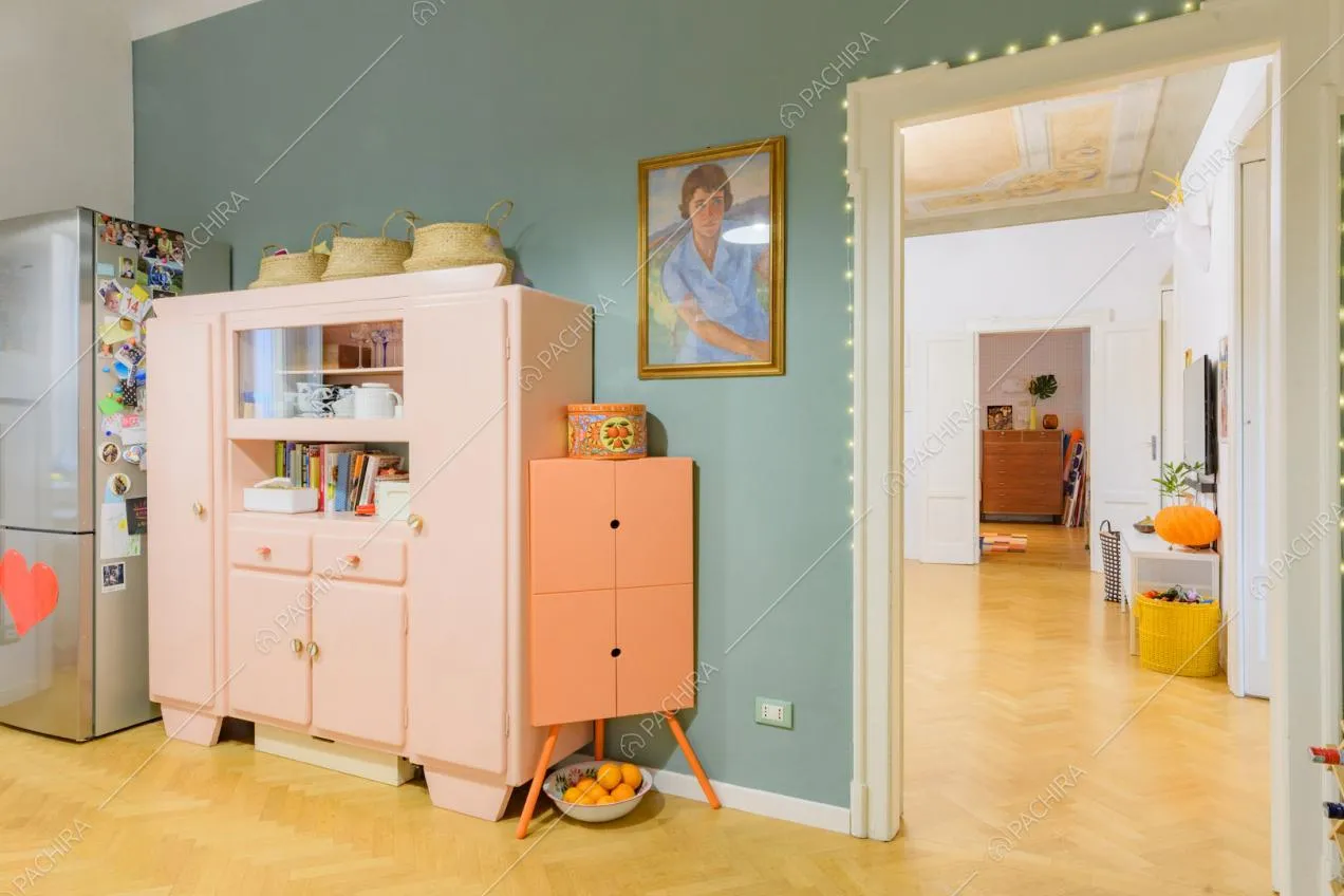 Credenza rosa nella cucina con parete azzurra e pavimento in parquet a spina di pesce