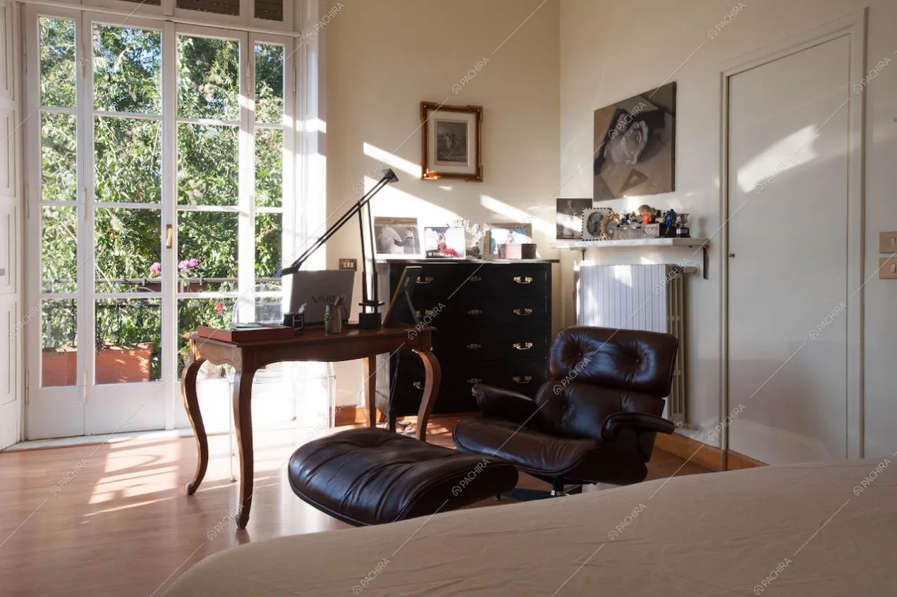 Camera da letto con poltrona e poggiapiedi neri e vetrata luminosa