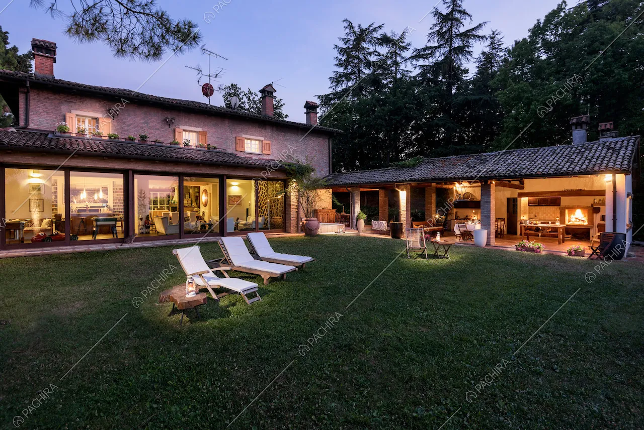 Nell'ampio giardino privato lettini bianchi, veranda e vista sull'open space della location attraverso le vetrate