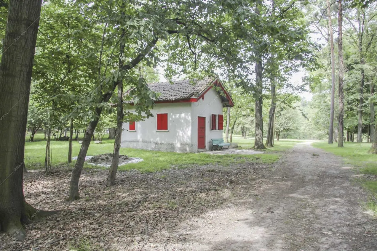 Dépendance bianca, con porta e finestre rosse, nel parco della location