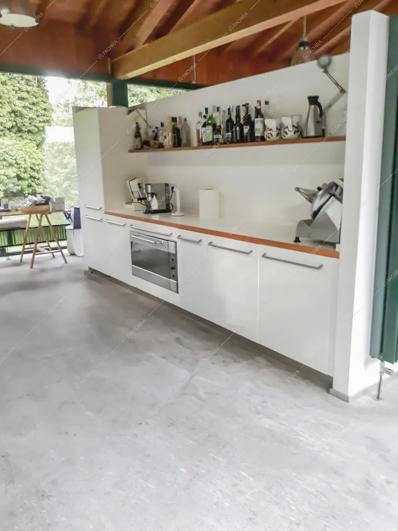 Cucina bianca a muro nello chalet con soffitto in travi in legno a vista