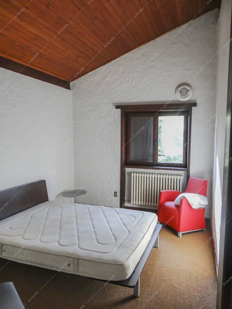 Camera da letto matrimoniale dalle pareti bianche e con soffitto in legno a vista