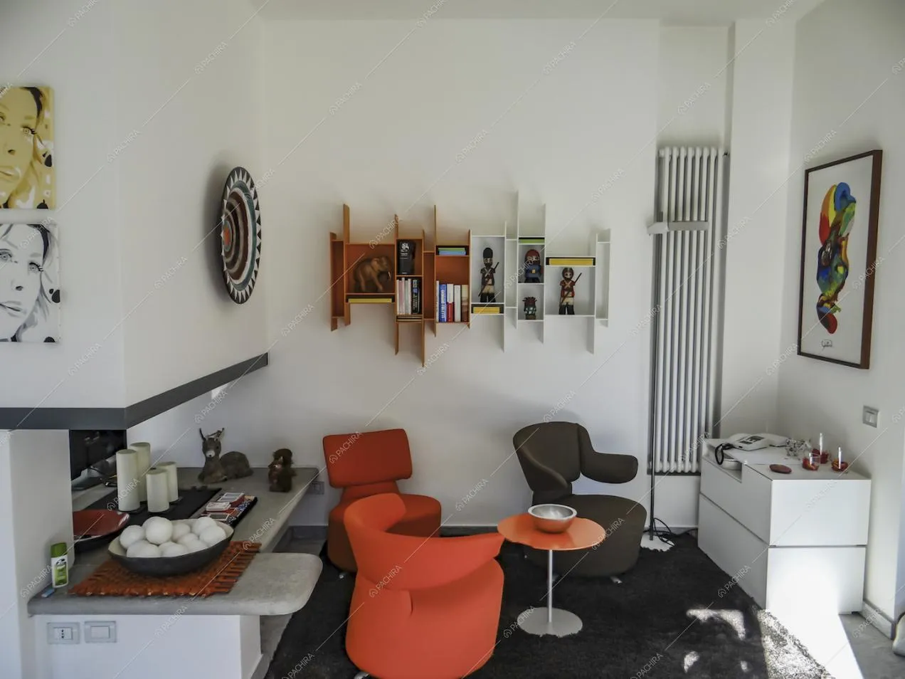 Nella sala dalle pareti bianche, poltrone di design e tavolino con piano in pietra